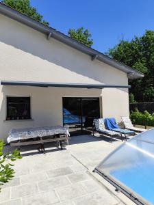 a patio with two loungers and two chairs in front of a building at Le petit nid dans les bois in Castres-Gironde