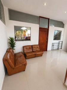 a living room with two brown leather couches at Hospedaje Cocos House Talara - amplias habitaciones, Buena Ubicacion in Talara