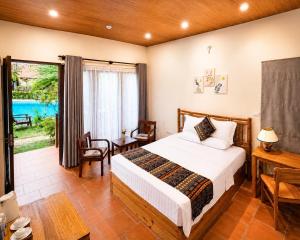 a bedroom with a bed and a table and a window at Wildland Resort in Phú Quốc