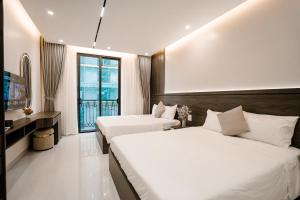 a hotel room with two beds and a television at Vui Hotel in Sầm Sơn