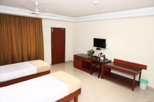 a hotel room with two beds and a desk and a television at Dhanunjayas Luxury Hotel in Hosūr
