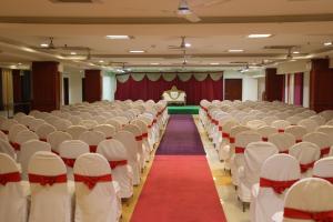 an empty hall with white chairs and a red carpet at Dhanunjayas Luxury Hotel in Hosūr