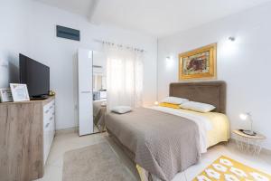 a white bedroom with a bed and a television at Apartments Gabi&Zdenka Tivat in Tivat