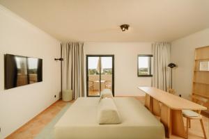 a room with a bed and a table and windows at Vale d'El Rei Hotel & Villas in Carvoeiro