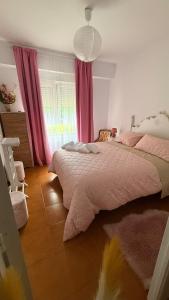 a bedroom with a bed with pink sheets and a window at Apartamento MILA centro in Comillas