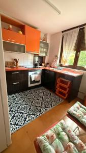 a kitchen with orange cabinets and a black and white rug at Apartamento MILA centro in Comillas