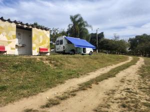 a camper with a blue roof parked next to a dirt road at Pousada Sítio do Aconchego Porto Feliz in Pôrto Feliz