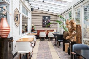 a restaurant with white chairs and tables and windows at Hotel Zeerust in De Koog