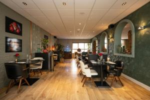 a restaurant with black tables and white chairs at Hotel Zeerust in De Koog +19 photos