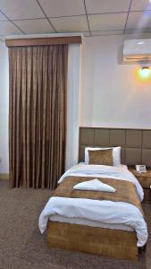a bedroom with a large bed and a window at Hamilton Plaza Hotel in Diyānah