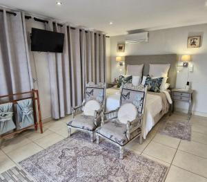 a bedroom with a bed with two chairs and a television at A Time And A Place in Plettenberg Bay +51 photos
