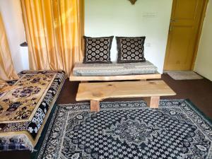 a room with two beds and a table and a rug at Tiny house soyal in Kulu