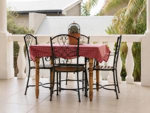 a table with two chairs and a table with a red table cloth at Alimento Guest House in Upington +11 photos