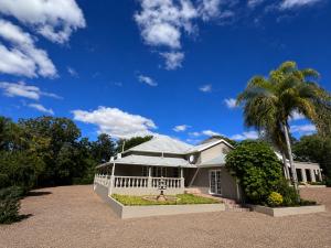 a large white house with a palm tree at Alimento Guest House in Upington