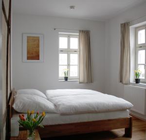 ein weißes Schlafzimmer mit einem Bett und zwei Fenstern in der Unterkunft Pension Sackpfeifenmühle in Erfurt