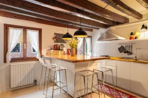a kitchen with wooden ceilings and bar stools at Erbe Canal View Private House in Venice +17 photos