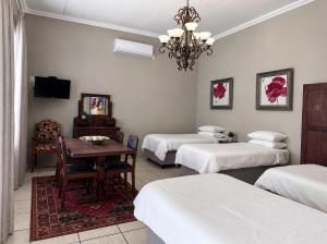 a room with three beds and a table and a chandelier at Alimento Guest House in Upington