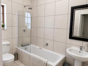 a bathroom with a tub and a toilet and a sink at Alimento Guest House in Upington