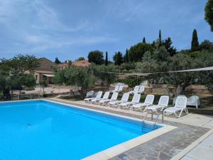 a swimming pool with white chairs next to a house at Agriturismo Case al Sole in Loreto