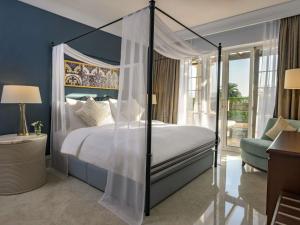 a bedroom with a canopy bed and a chair at Mövenpick Resort & Residences Aqaba in Aqaba