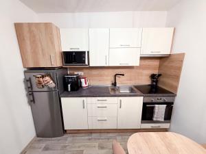 a kitchen with white cabinets and a stainless steel refrigerator at KaiTea Suites in Všemina