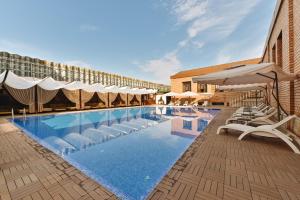 a large swimming pool with white chairs and umbrellas at Ichan Qal'a Premium Class Hotel in Tashkent