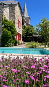 a garden with pink flowers in front of a building at Le couvent de Jouels in Sauveterre-de-Rouergue
