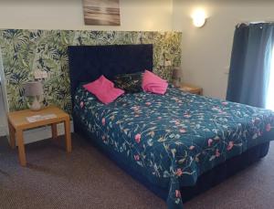 a bedroom with a bed with pink pillows on it at Marmion House Hotel in Wisbech