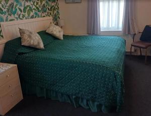 a bedroom with a green bed with pillows on it at Marmion House Hotel in Wisbech