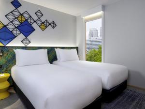 a bedroom with a large white bed and a window at ibis Styles Bangkok Silom in Bangkok +135 photos