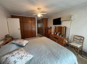 a bedroom with a large bed with a ceiling fan at Wageney2us in Kempton Park +2 photos
