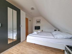 a bedroom with a white bed and a tv at Wolles Sonnenhaus in Wirdum