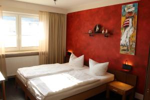 a bedroom with a bed with a red wall at Osterberg - Restaurant und Hotel in Hildesheim