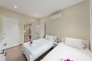 two beds in a bedroom with white sheets and pink flowers at Casa Verde - Blije Rust I in Dorp Sint Michiel