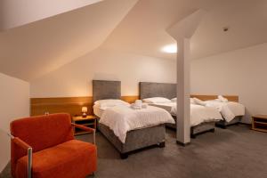 a room with two beds and a chair in it at Hotel Novy Kastiel - Self check-in in Topoľčany +77 photos