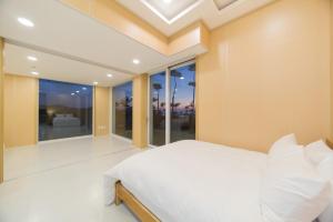 a bedroom with a white bed and a large window at The Mare Pool Villa Pension in Taean