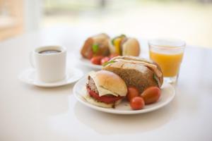a plate of food with a sandwich and a glass of orange juice at The Mare Pool Villa Pension in Taean