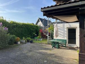 a green picnic table next to a house with an umbrella at Königshof Studio in Monschau