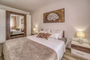 a bedroom with a large white bed and a mirror at Apartments Doris in Malinska