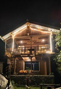 a wooden house with a deck at night at Tiny house soyal in Kulu +7 photos