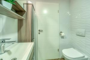 a white bathroom with a toilet and a shower at Apartments Doris in Malinska +37 photos