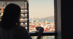 a woman looking out of a window at a city at Season Suite Apart-Hotel in Batumi +37 photos