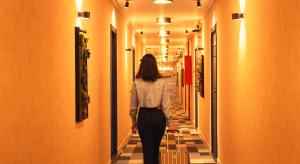 a woman walking down a hallway in a building at Season Suite Apart-Hotel in Batumi