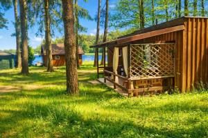 a small wooden cabin in the grass with trees at Mazury - Ruś domki wypoczynkowe nad samym jeziorem in Ruś +8 photos