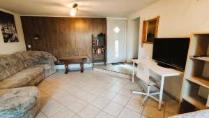 a living room with a couch and a desk with a television at Souterrainwohnung in Niederau in Niederau +18 photos