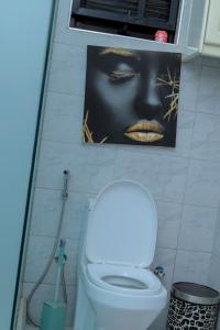 a bathroom with a toilet and a picture of a woman at Cozy Retreat in Kampala +10 photos