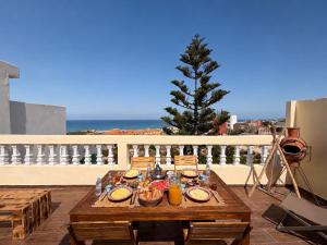 a table with food on top of a balcony at Happy Waves Morocco - Surf Hostel Tamraght in Tamraght Ou Fella