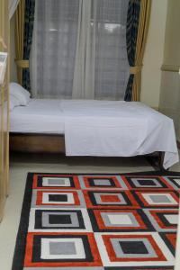 a bedroom with a bed and a rug on the floor at Cozy Retreat in Kampala