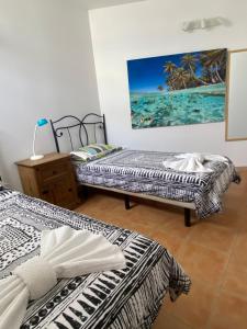 two beds in a room with a painting on the wall at Atlantic Breeze House I Double Rooms at EL CAMPANARIO I 5 minutes from Popcorn Beach in Corralejo