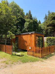 a wooden building with a fence in a yard at Bungalow Gerês - Pichoses Camping in Rio Caldo